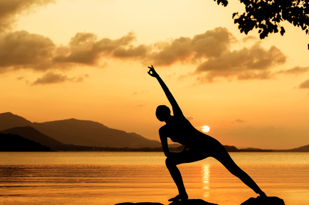 Silhouette junge Frau praktiziert Yoga Sonnenuntergang Hintergrund - Foto, Bild