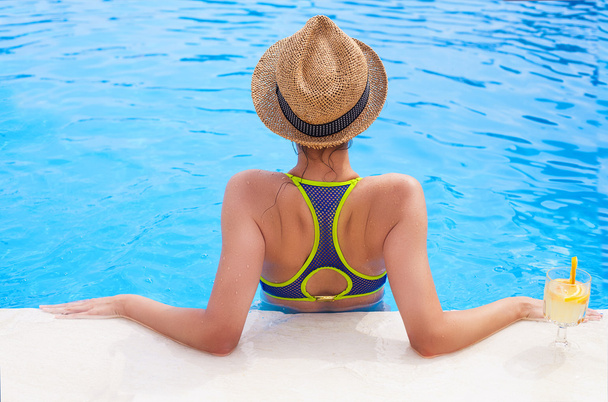 Гарненька брюнетка жінка насолоджується лимонадом у басейні
 - Фото, зображення