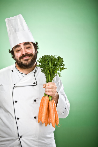 happy relaxed chef cooking carrots isolated on green - Fotoğraf, Görsel