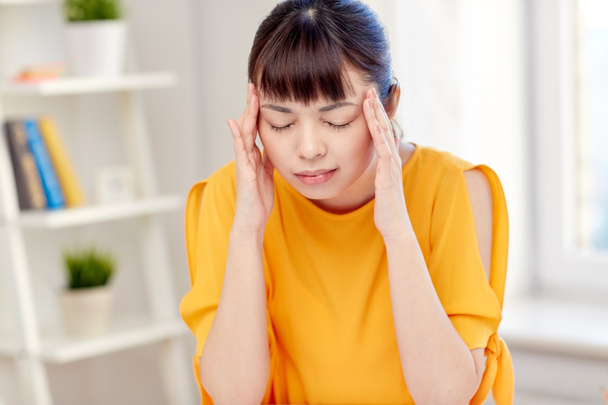 tired asian woman suffering from headache at home - 写真・画像