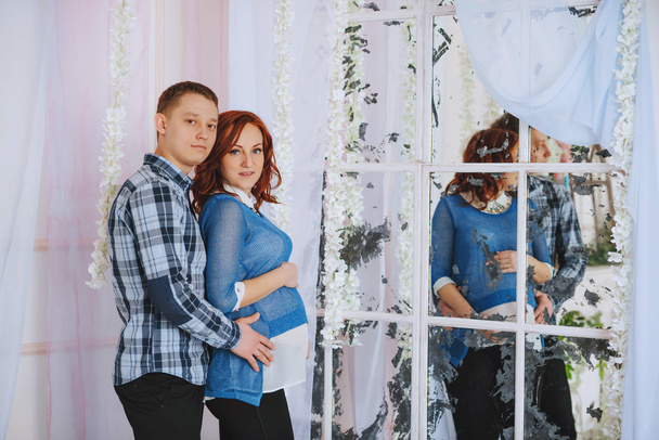 Pregnant family. The husband embraces his wife. Stand near the mirror - Фото, изображение