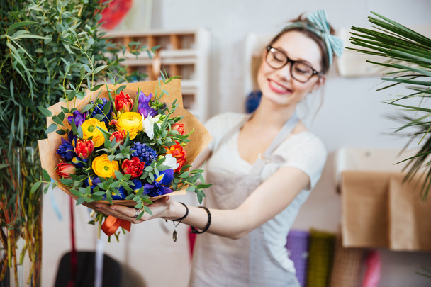 Cheerful woman florist showing bouquet of colorful flowers  - Fotoğraf, Görsel