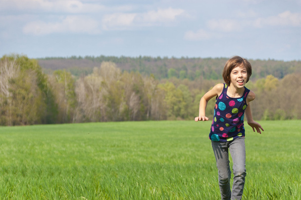 Happy active girl running on green field - Foto, afbeelding