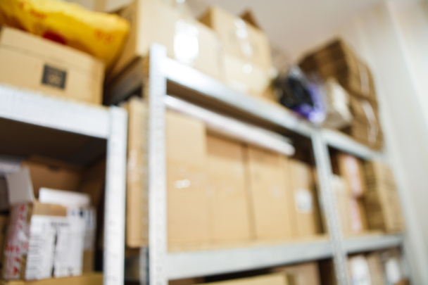 Blurred image of storage racks with carton boxes in warehouse for small business - Photo, Image