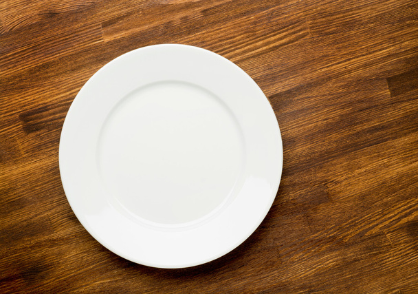 Empty white plate on wooden table top view - Fotó, kép