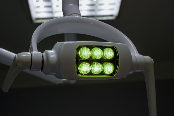 Λαμπερό λευκό ιατρικό ασκίαστος Λάμπα με πράσινο φως στο σκοτεινό δωμάτιο - Φωτογραφία, εικόνα