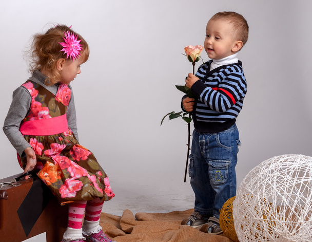 Pieni poika antaa tytölle ruusun, joka on eristetty valkoisella
 - Valokuva, kuva