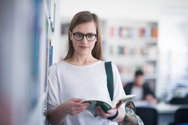 portrait of female student reading book in library  - Foto, Bild