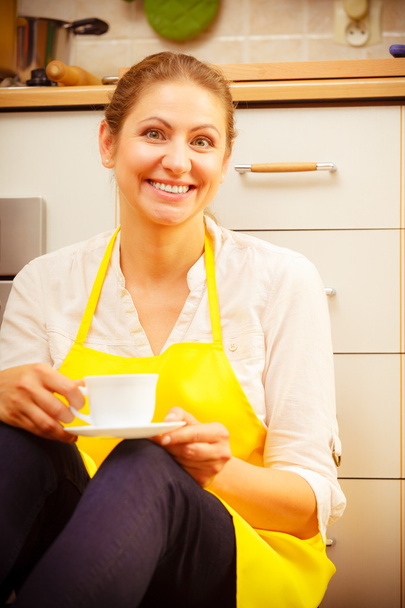 Mature woman holding cup of coffee in kitchen. - Foto, imagen