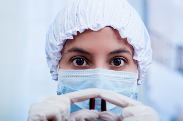 Closeup headshot nurse wearing bouffant cap and facial mask holding up two pill capsules for camera - Photo, image