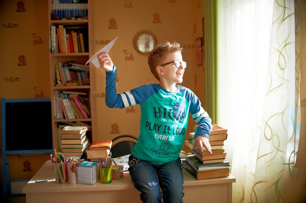 menino com origami brinquedo avião em casa
 - Foto, Imagem