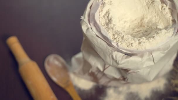 Flour bag on wooden table, bouquet of wheat, rolling pin and wooden spoon - Footage, Video