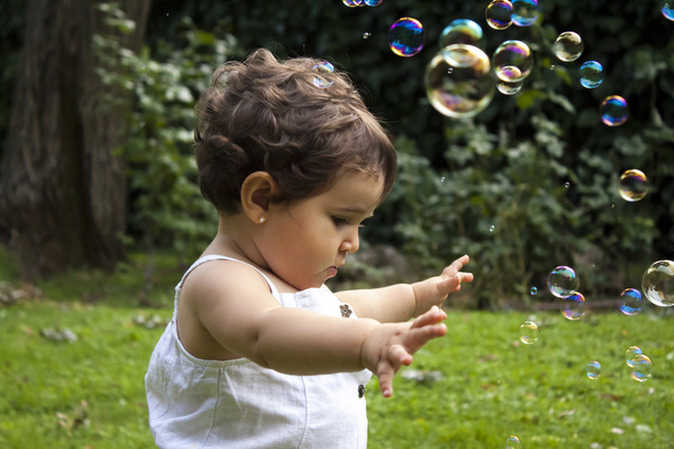 Girl playing with soap bubbles in the garden - Photo, Image