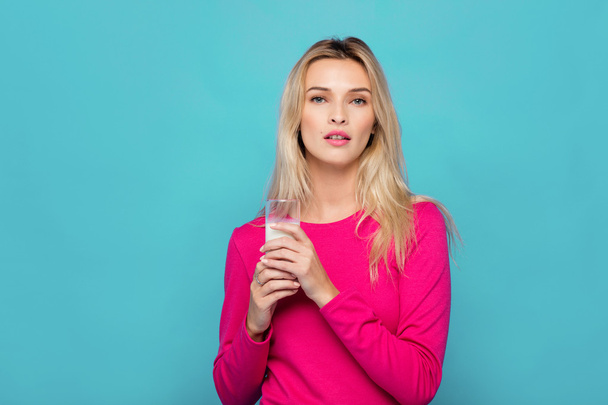 Blonde young woman a glass of milk on blue - Foto, imagen