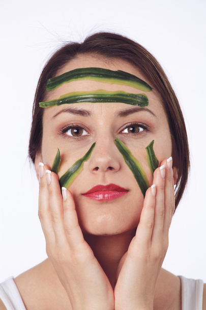 Young woman with her face covered with cucumber slices - Фото, изображение