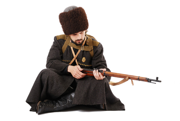 Cosaco ruso inspeccionando un rifle en posición sentada. La historia viva
. - Foto, imagen