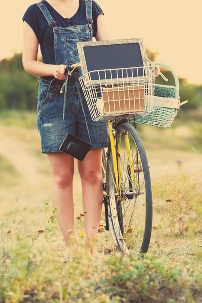 Νεαρή γυναίκα με ποδήλατο στο λιβάδι - Φωτογραφία, εικόνα