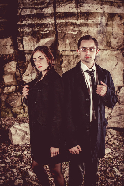 Couple of well dressed peolpe on the dark rocks background. - Photo, Image