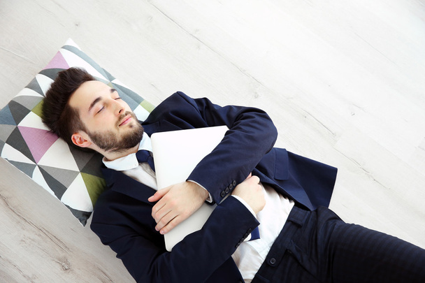 Young tired businessman with laptop sleeping  - Foto, Bild