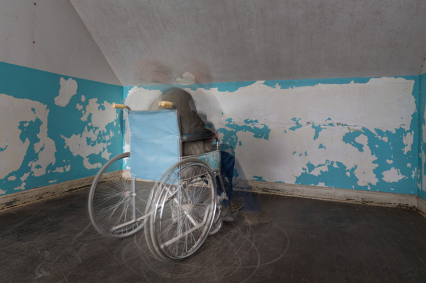 Gespenstische Gestalt bewegt sich im Rollstuhl in Zimmerecke - Foto, Bild
