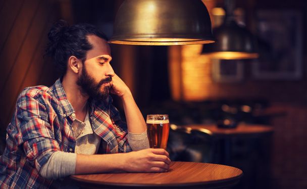 unhappy lonely man drinking beer at bar or pub - Foto, Imagen