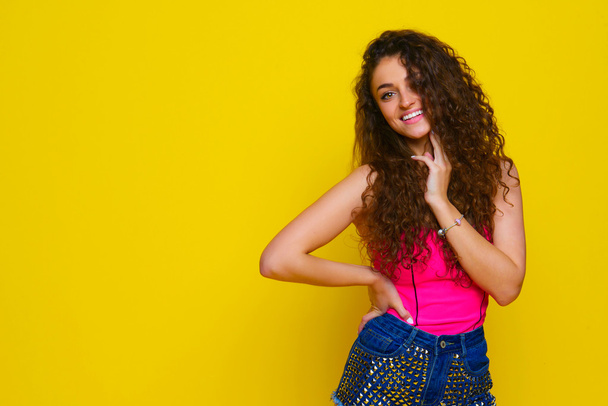 Young and beautiful curly girl in a pink shirt and blue shorts o - Foto, Imagen