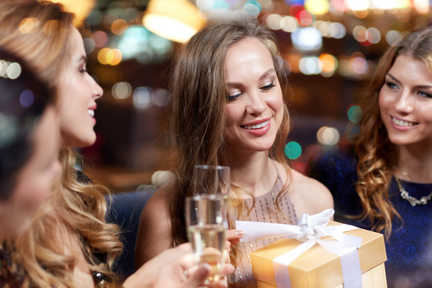 happy women with champagne and gift at night club - Foto, afbeelding