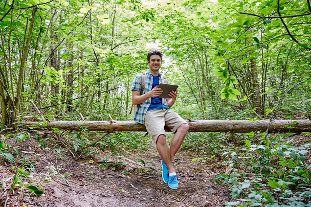 happy man with backpack and tablet pc in woods - Fotó, kép
