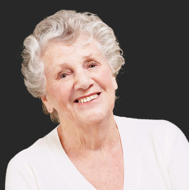mujer mayor sonriendo sobre un fondo negro
 - Foto, Imagen
