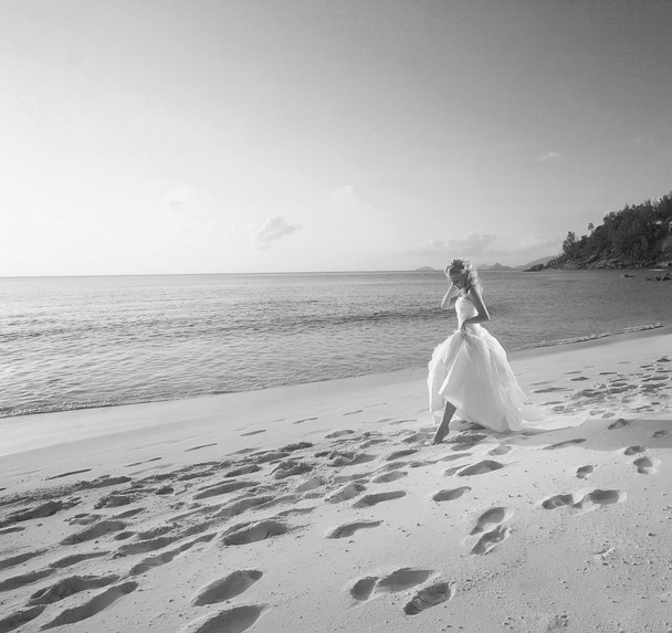 Beautiful lovely bride walking on the beach on sunset. Grayscale - Fotoğraf, Görsel