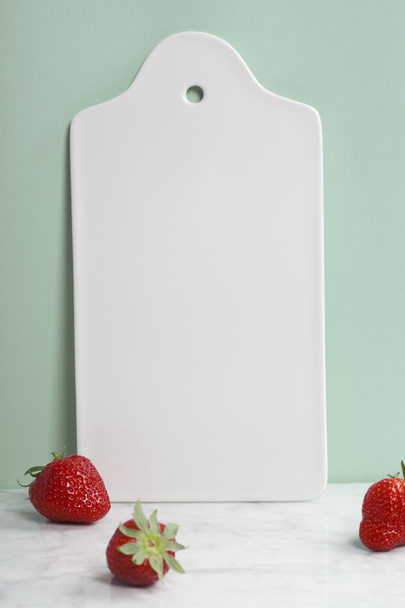 White ceramic serving board and berry over light blue background - Foto, imagen
