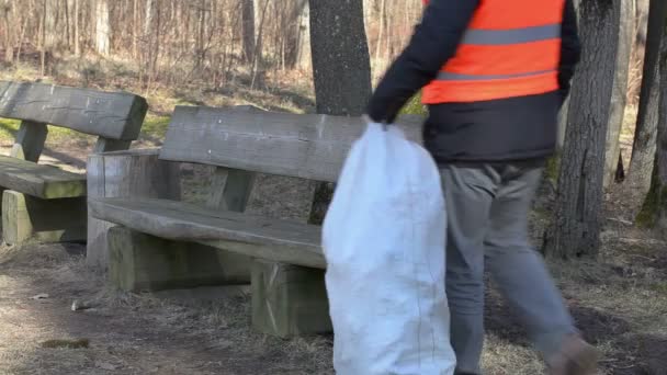 Μαν ελέγξετε τσάντα πλαστικές φιάλες σε παγκάκι στο πάρκο  - Πλάνα, βίντεο