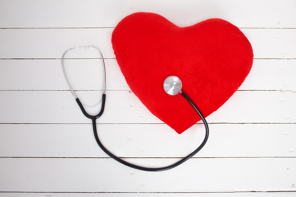 Stetoscopio con cuscino cuore rosso su sfondo di legno bianco
 - Foto, immagini