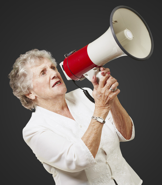 Портрет старшої жінки, що тримає мегафон на чорному тлі
 - Фото, зображення