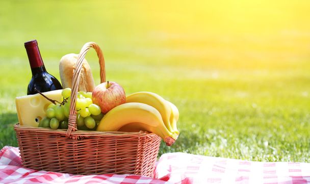 Picnic basket with food on green grass - Fotó, kép