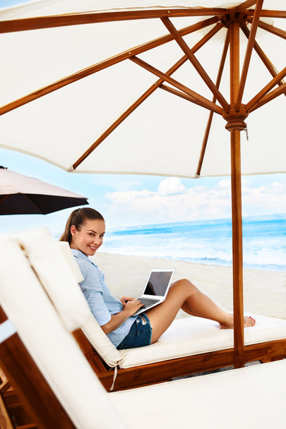 Женщина расслабляется с помощью компьютера на пляже
. - Фото, изображение