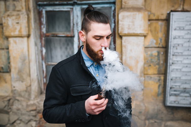 Hombre con barba fumar cigarrillo electrónico al aire libre
 - Foto, imagen