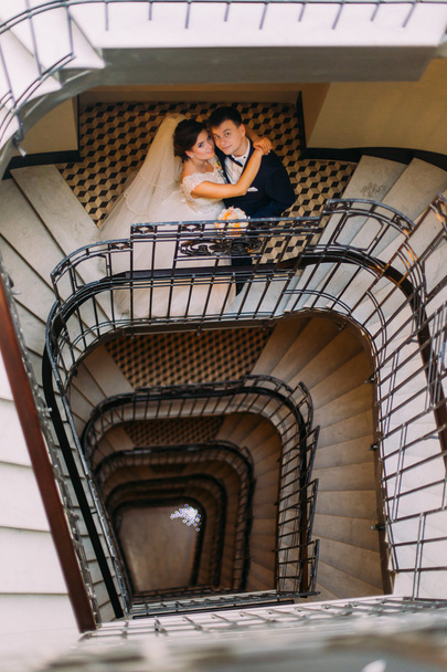 Young married couple standing face-to-face at the stairs and holding hands - Photo, image