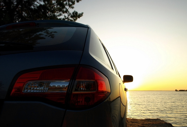 Car on the sea beach at sunset  - Фото, изображение