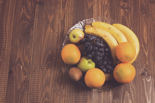 Kiwi, laranjas, uvas, bananas estão no prato
 - Foto, Imagem