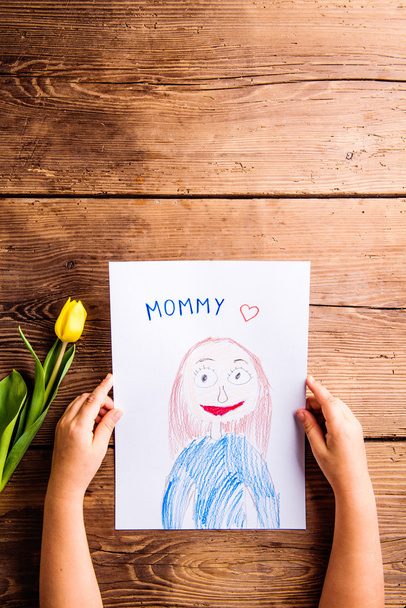 Girl holding drawing of her mother and yellow tulip. - Foto, imagen