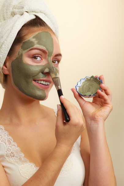 Femme appliquant avec un masque de boue d'argile brosse sur son visage
  - Photo, image