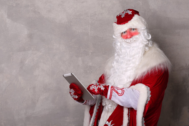 Дед Мороз держит планшет и смотрит в камеру
 - Фото, изображение