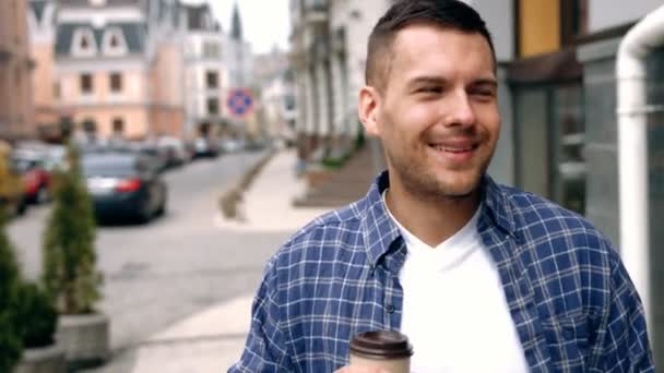 Stadtstil. schöner junger Mann in schicker Freizeitkleidung, Kaffeetasse haltend und auf der Straße wegschauend - Filmmaterial, Video