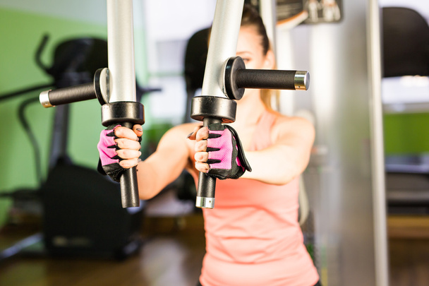 спорт, фитнес, бодибилдинг, командная работа и концепция людей - молодая женщина сгибает мышцы на тренажере
 - Фото, изображение