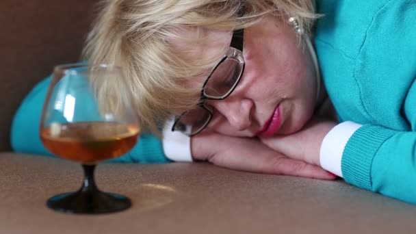 Nukkuva nainen makaa sohvalla lasin kanssa konjakkia
 - Materiaali, video