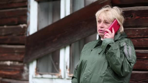 Nő a zöld esőkabát beszél a mobiltelefonján - Felvétel, videó