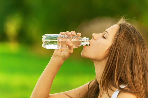 Young woman drinking bottle of water - Fotoğraf, Görsel