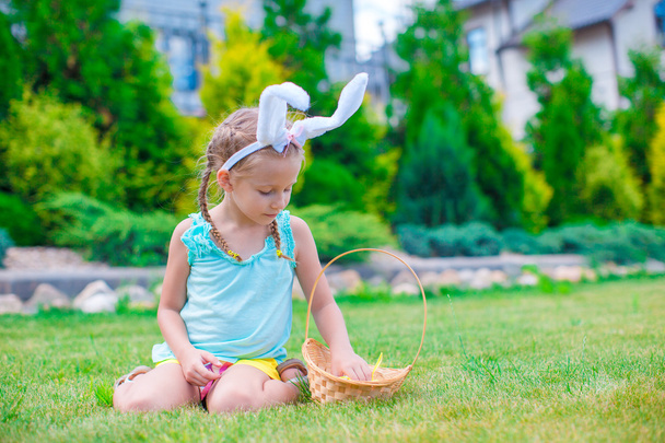 Adorable little girl wearing bunny ears holding basket with Easter eggs - Foto, Imagen