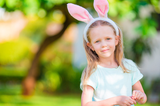 Adorable little girl wearing bunny ears with Easter eggs on spring day - Photo, Image